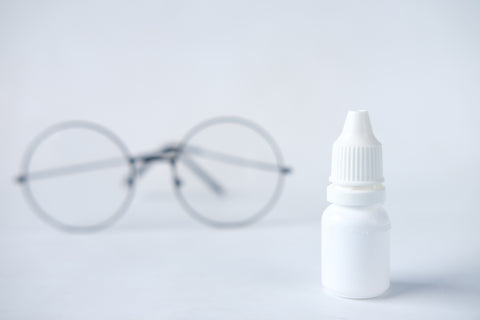 eye drops bottle in front of spectacles