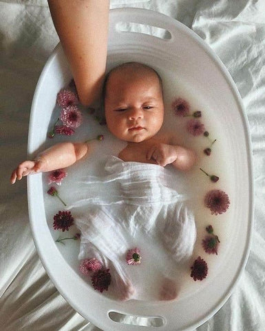 newborn baby in a milky bath with botanical flowers
