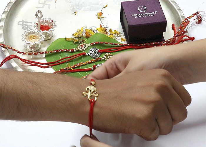 Sister tying silver rakhi on brother's wrist