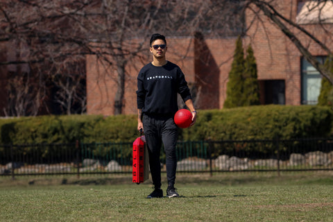 Ambassador holding the boardball board and ball in hand at the park