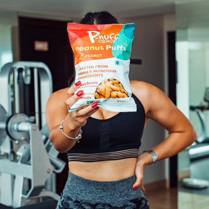Woman in gym holding high protein snack.