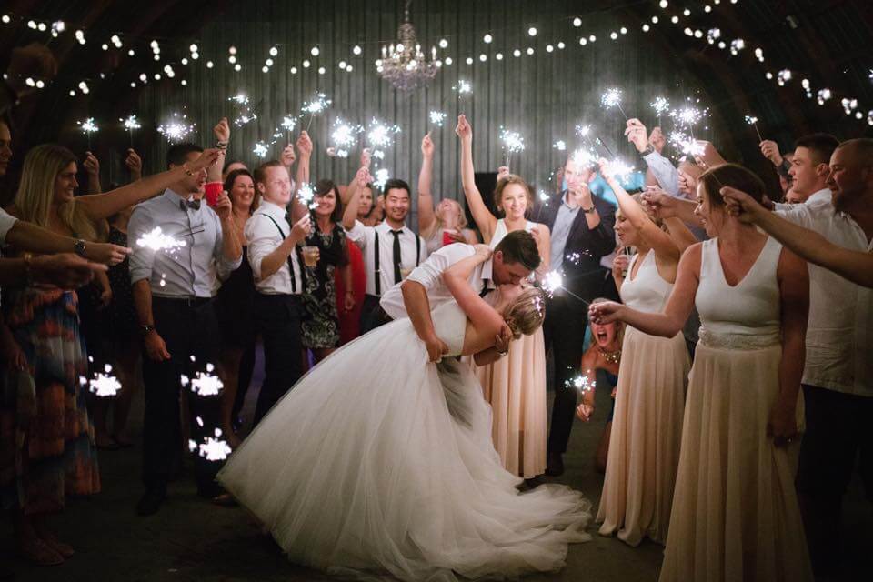 groom dips his bride and kisses her while their guests surround them in this spectacular wedding sparkler exit by Jennifer Hopkins
