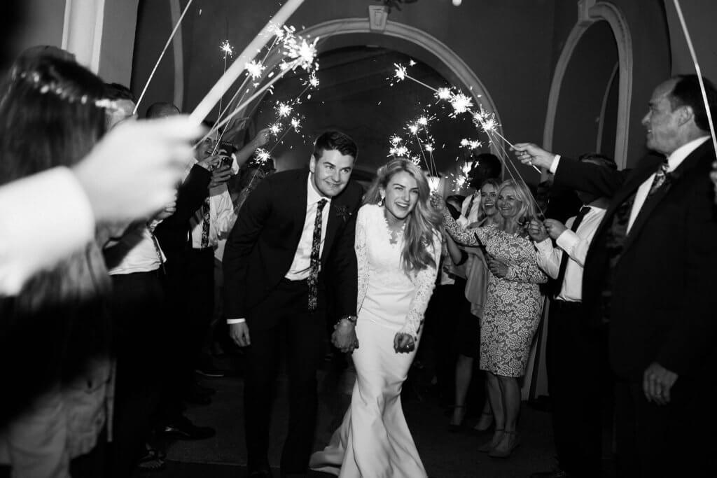 black and white of a bride and groom's wedding sparkler exit through a tunnel of guests