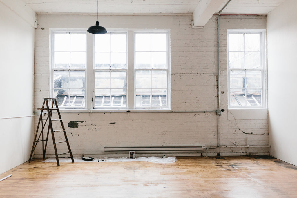 empty loft studio in a big city with whitewashed pane windows and a ladder in one corner