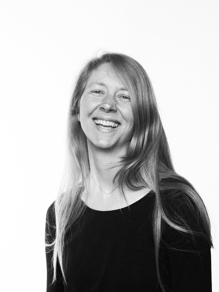 black and white image of a white woman with long blonde hair laughing in studio using v-flats light shaping tools.