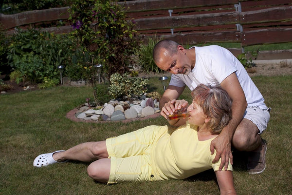 first aid for dehydration: man helping the old woman to drink