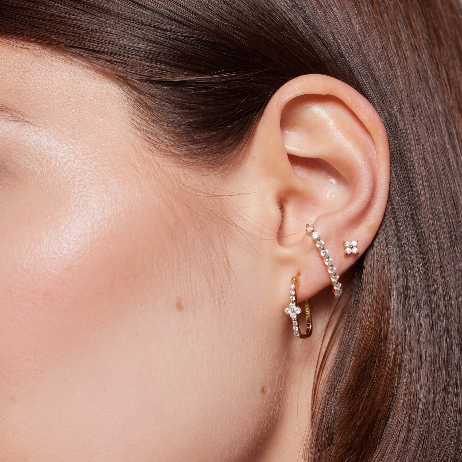 Close-up of a woman's ear with multiple earrings.