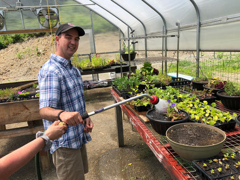 Participant in the Vocational Agriculture program waters plants in the Cultivating Dreams greenhouse