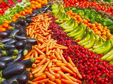 a picture of brightly colored fruits and vegetables lined up in rows.  Eggplant, carrots, bananas, cherries and more can all be seen.