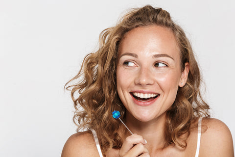 A woman smiling while holding a Fresh Tips disposable toothbrush.