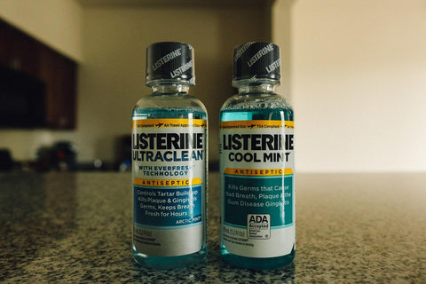 2 small bottlers of Listerine sit on a counter. 