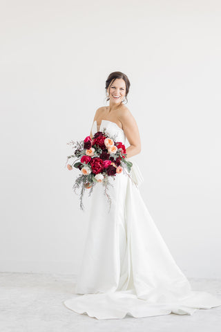 Jewel-toned wedding bouquet featuring peonies, garden roses, ranunculus, winter greenery and peach accents, in Fargo, ND