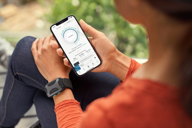 Woman wearing her Apollo on her wrist while using the Apollo Neuro app on her iPhone