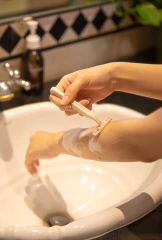 Woman Shaving Hair on Arm With Razor