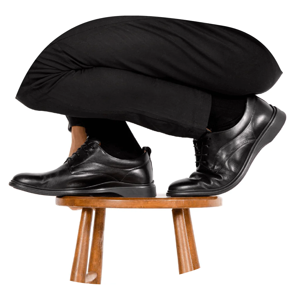 A man wearing The Original dress shoes in the color obsidian from Amberjack while balancing on a stool