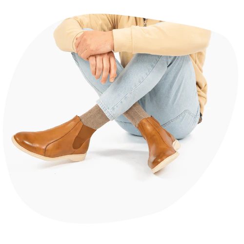 A man sits on a white floor in his Honey & Cream men’s slip-on dress shoes