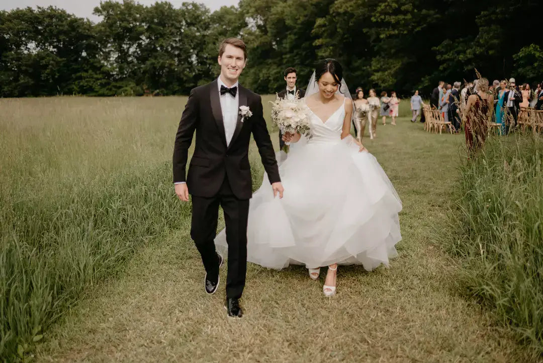 A newlywed groom walking with his wife and wearing tux shoes from Amberjack