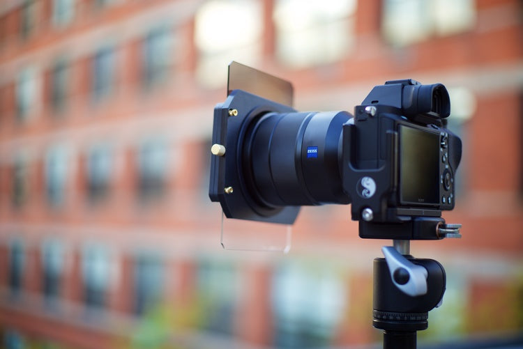 A DSLR style camera and lens with a Formatt Hitech filter and filter holder attached to the front of the lens