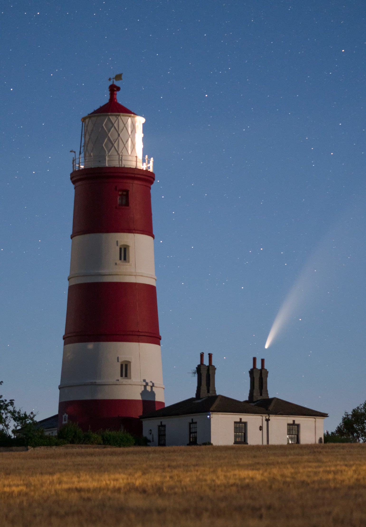 Neowise comet as photographed at night against a Norfolk, UK lighthouse and starlight sky
