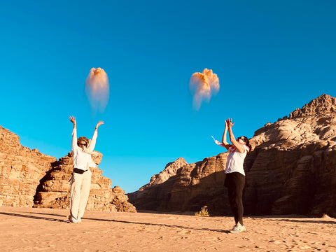 Tara and Annabelle throw sand into the air; Wadi Rum, Jordan