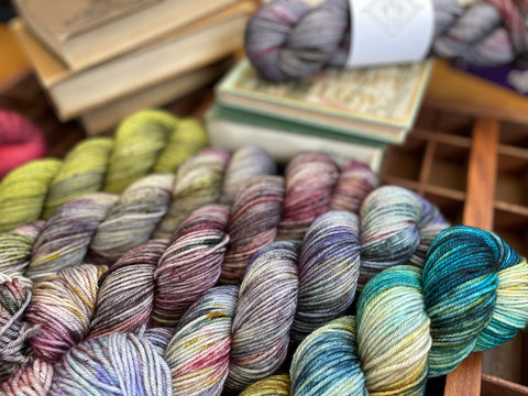 Colorful skeins of hand dyed yarn near books.