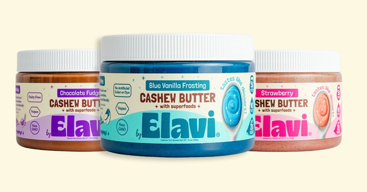 Three jars of Elavi cashew butter in different flavors: chocolate fudge, blue vanilla frosting, and strawberry.