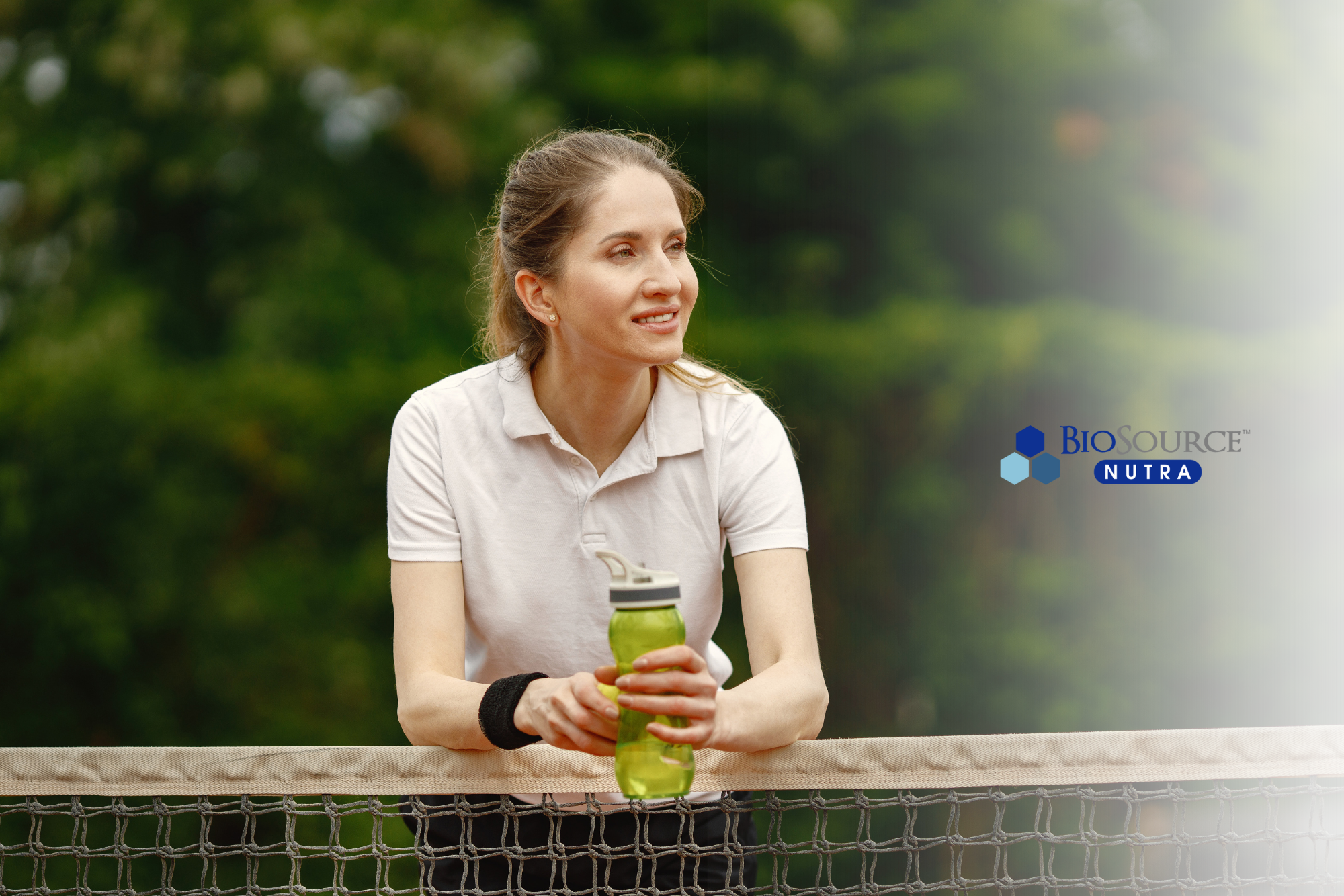 A young woman takes a break from playing tennis to hydrate