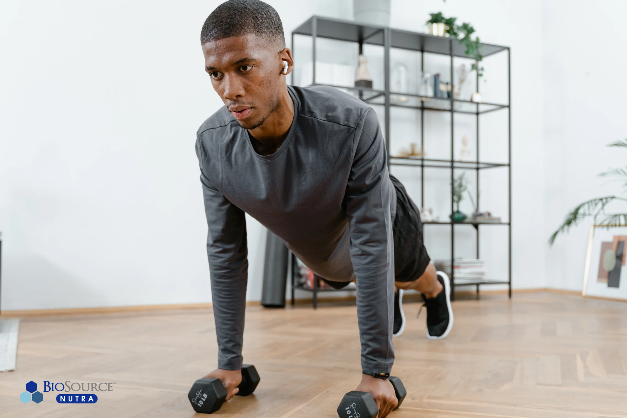 A young man does a plank with dumbbells