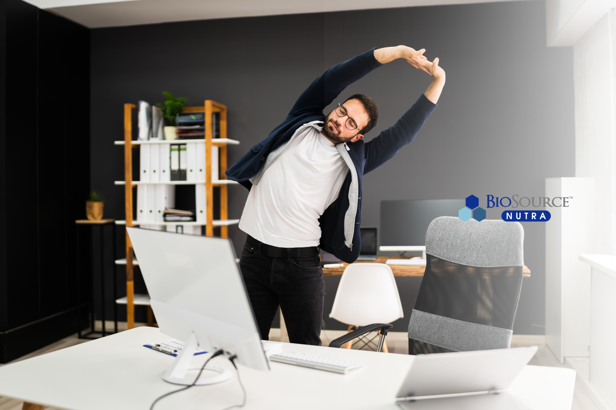 A young man takes a stretch break at his desk