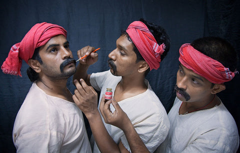 Three Indian men actors in bright pink head pieces
