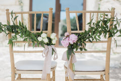 Two wedding chairs at Spanish wedding venue adorned with pink and white flowers and trailing silk ribbons