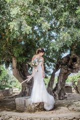 Spanish olive grove wedding venue with bride in front of tree holding bouqeut with trailing silk ribbons