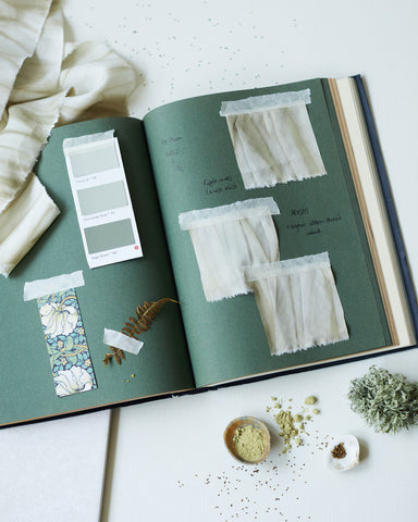 Artist notebook with green colour inspiration, plant dyed silk ribbons, weld seeds and weld powder
