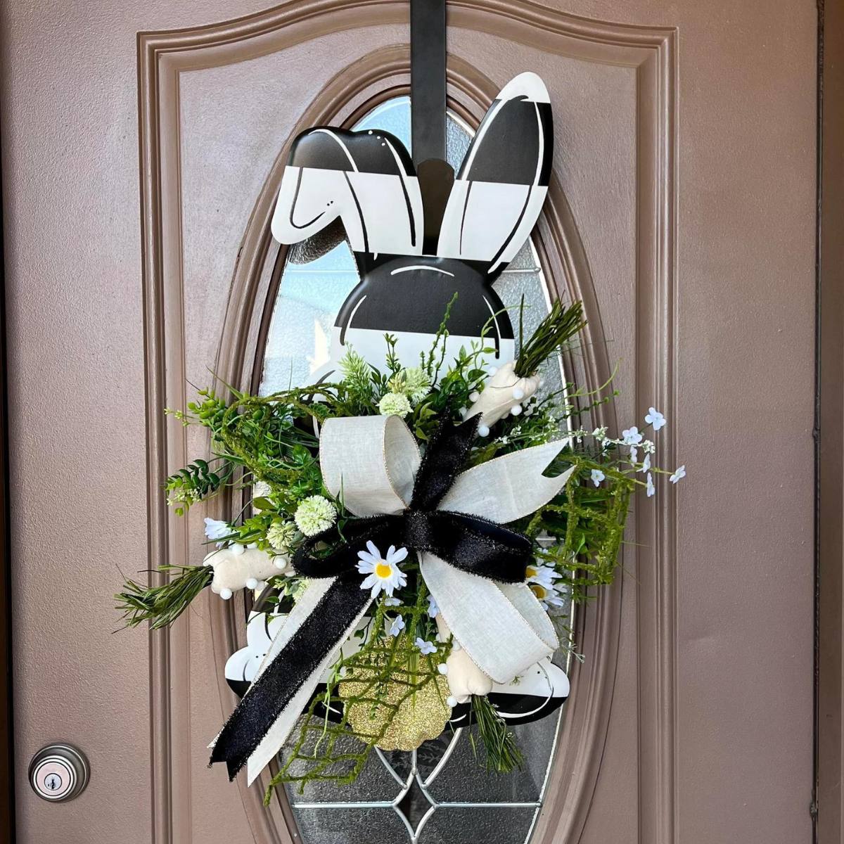 black and white striped metal bunny door hanger decorated with florals and a bow
