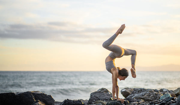 The model is wearing a WISKII activewear set, practicing yoga by the seaside.