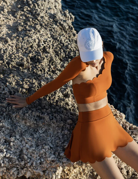 A model showcasing vibrant sunset terracotta activewear on the mountainside.