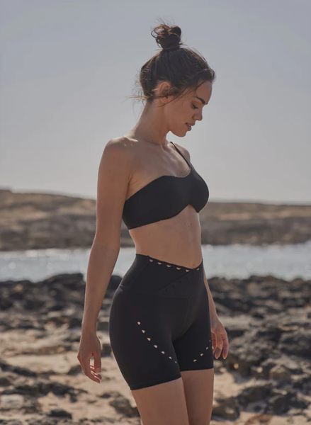 The model showcases the black WISKII seamless sports bra and shorts by the seaside.