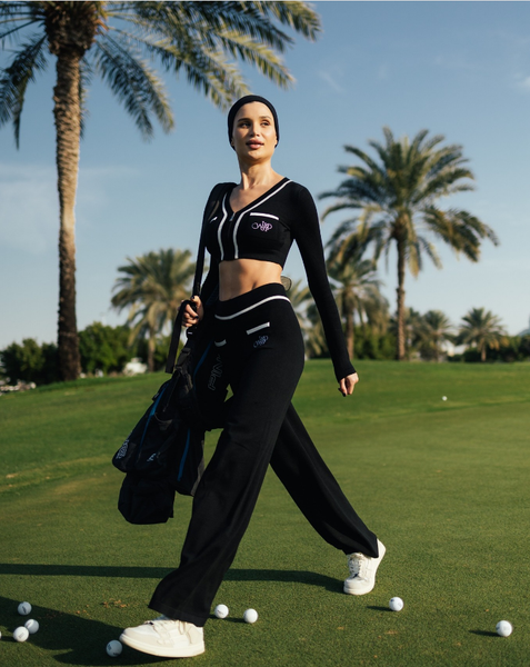 Model wearing black sports suit playing golf on golf course