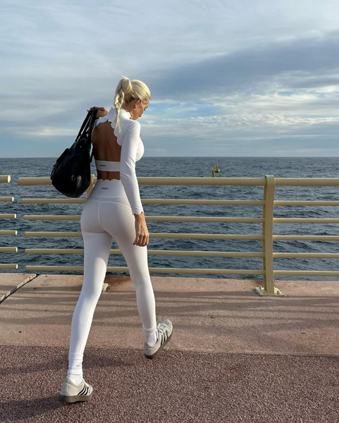 Model in white sportswear preparing to workout on the beach