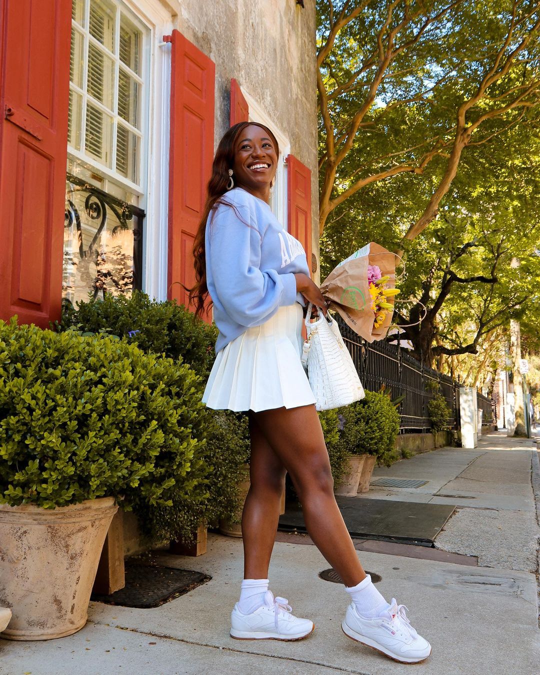 lady wears a sweatshirt with a tennis skirt at outdoors