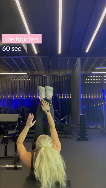 A model performing toe touches exercise in the gym.