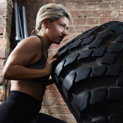 a woman exercising pushing a tire