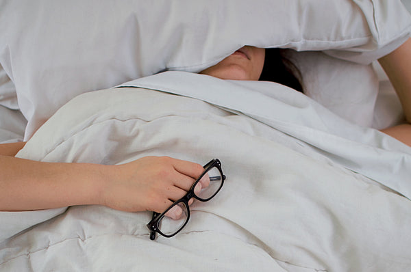 The complete guide to the AIP diet: An exhausted woman hides under her pillow in bed