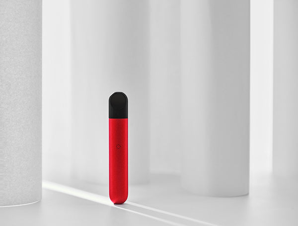 A red vape pen stands on end against a white background.