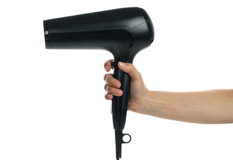 A woman holds a hair dryer in her hand.