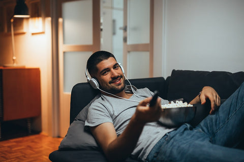 A man listens to music via headphones as he relaxes on his sofa.