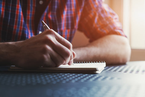 Man writes in a journal.