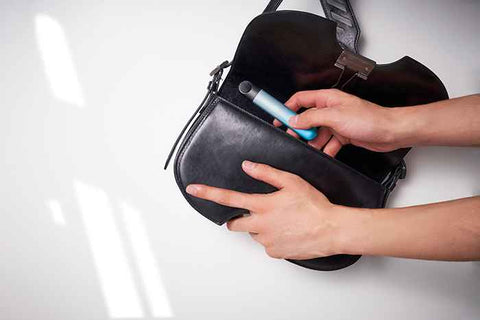 Woman pulling out a vape device from a black purse.