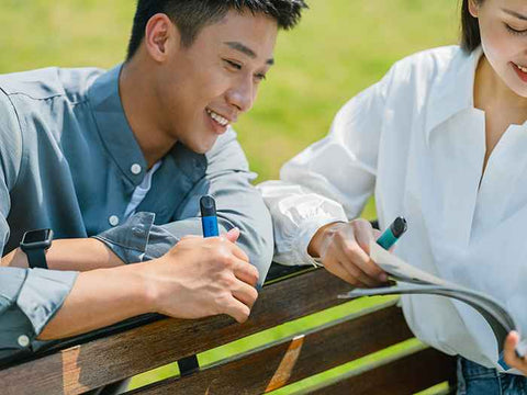 A couple holding RELX vape devices in their hands as they look at a book.