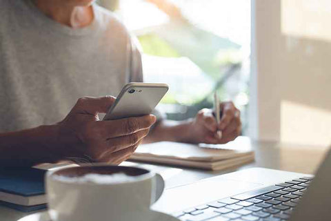 Man writing down notes from his mobile phone